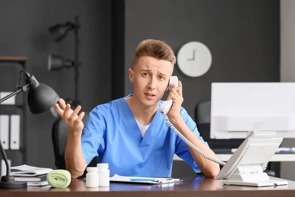 Confundido Asistente Médico Masculino Hablando Por Teléfono Mesa Clínica — Foto de Stock