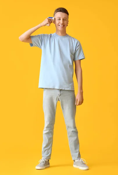 Mladý Muž Infračerveným Teploměrem Měří Teplotu Žlutém Pozadí — Stock fotografie