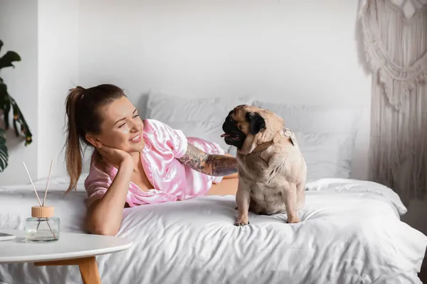 Молодая Женщина Милой Собакой Мопсом Лежит Кровати — стоковое фото