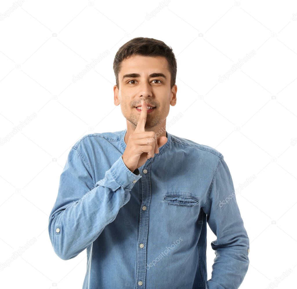 Young gossip man showing silence gesture on white background