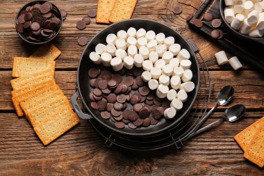 Pişmemiş S 'mores soslu tava ahşap arka planda.