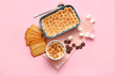 Lezzetli S 'mores soslu fırın ve ramekin pembe arka planda.