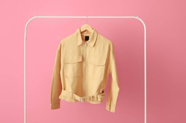 Pembe duvarın yanında şık sarı ceketli raflar.