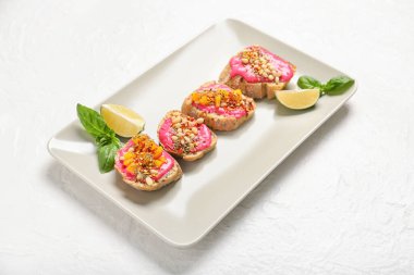 Lezzetli vejetaryen bruschetas tabağı ve açık arkaplanda limon.