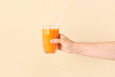 Arka planda bir bardak sağlıklı meyve suyu olan bir kadın eli.