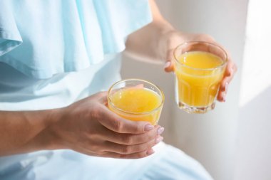 Odada sağlıklı meyve suyu bardakları olan bir kadın, yakın plan.