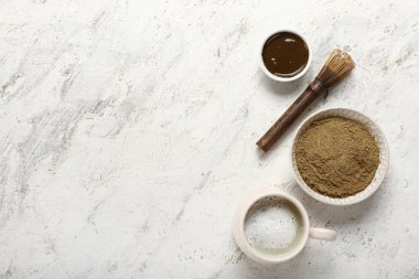 Hojicha pudralı kase, bir fincan çay ve hafif arka planda chasen.