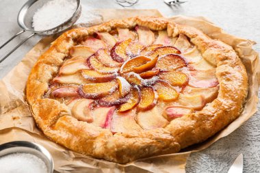 Açık arkaplanda lezzetli şeftali galetesi olan parşömen, yakın plan.