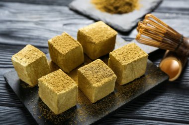 Koyu ahşap arka planda lezzetli hojicha şekerlemeleri olan tahta tahta kaplama, yakın plan.