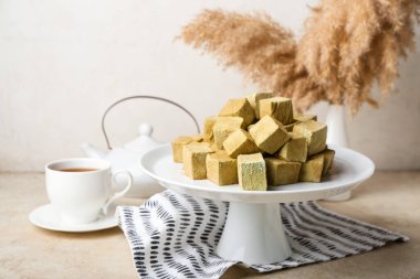 Lezzetli hojicha şekerlemeleri ve aydınlık masada bir fincan çayla ayakta durun.