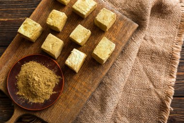 Lezzetli hojicha şekerlemeleri ve ahşap arka planda pudra olan bir tahta.