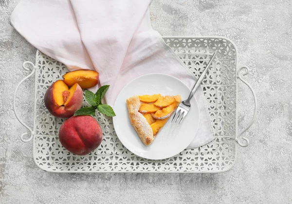 Plate with piece of tasty peach galette on light background