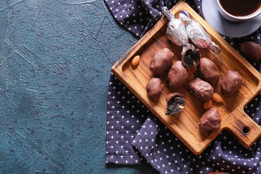 Lezzetli çikolata şekerli ahşap tahta ve renkli arkaplanda kuru erik.