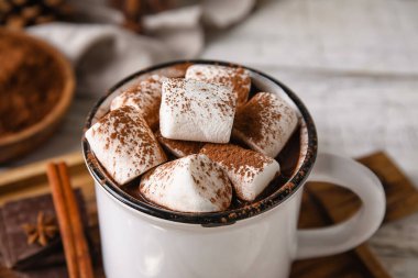 Ahşap arka planda bir kupa lezzetli sıcak çikolata, yakın plan.