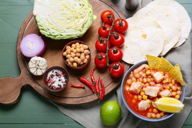 Lezzetli pozole çorbası ve ahşap arka planda malzemeler.