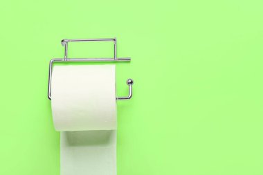 Yeşil arka planda tuvalet kağıdı rulosu olan tutucu