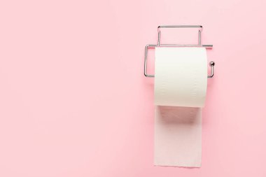Pembe arka planda tuvalet kağıdı rulosu olan tutucu