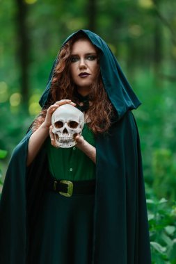 Yeşil ormanda kafatasları olan genç cadı.