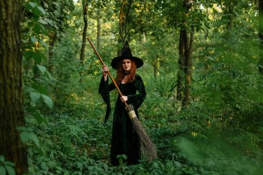 Yeşil ormanda süpürgeyle gezen genç cadı