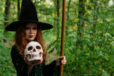 Yeşil ormanda kafatasları olan genç cadı.