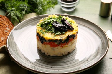 Lezzetli katmanlı salata, tabakta kuru erik, ahşap kaplama, yakın plan.