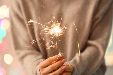 Bulanık ışıklara karşı maytap tutan kadın