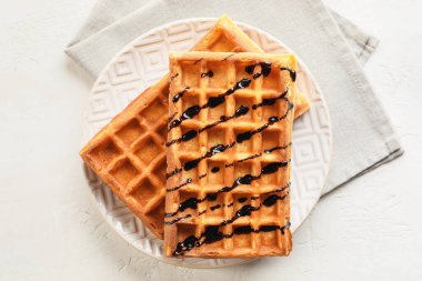 Lezzetli Belçika waffle tabağı ve açık arkaplanda çikolata sosu.