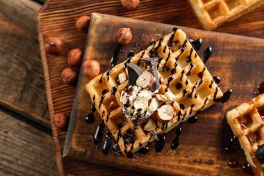 Tahta arka planda kremalı ve fındıklı lezzetli Belçika Waffle 'ları.