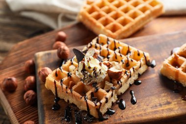 Tahta arka planda kremalı ve fındıklı lezzetli Belçika Waffle 'ları.