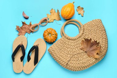 Hasır çanta, terlik, gözlük, balkabağı ve sonbahar yaprakları renk arkaplanda