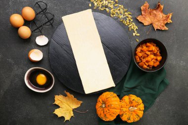 Koyu arkaplanda balkabaklı turta hazırlamak için ham hamur ve malzemeler