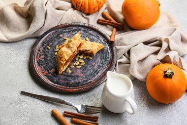 Lezzetli balkabaklı börek ve hafif arka planda süt tabağı.
