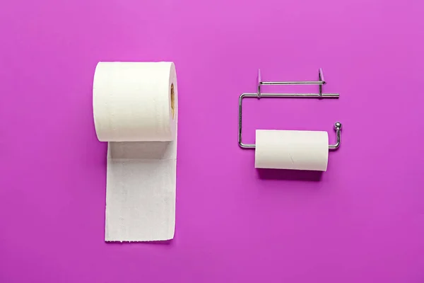 Holder with cardboard tube and toilet paper roll on purple background