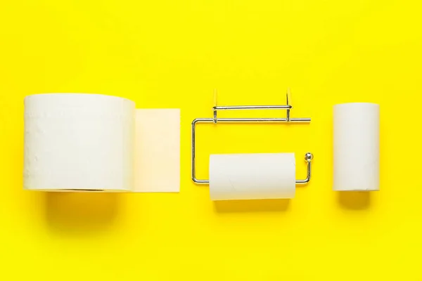 Holder with cardboard tube and toilet paper roll on yellow background