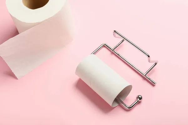 Holder with cardboard tube and toilet paper roll on pink background, closeup