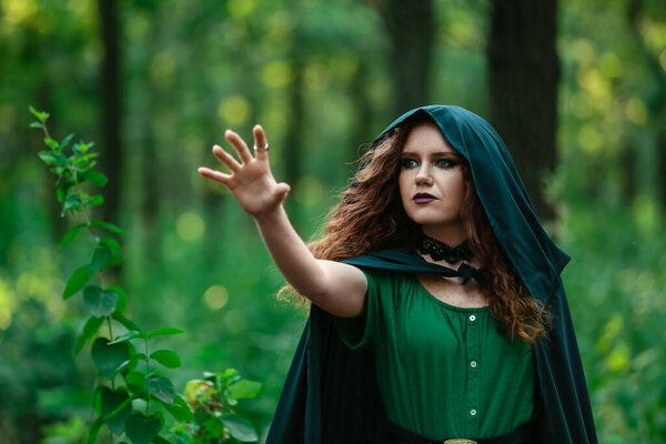 Young witch in green forest