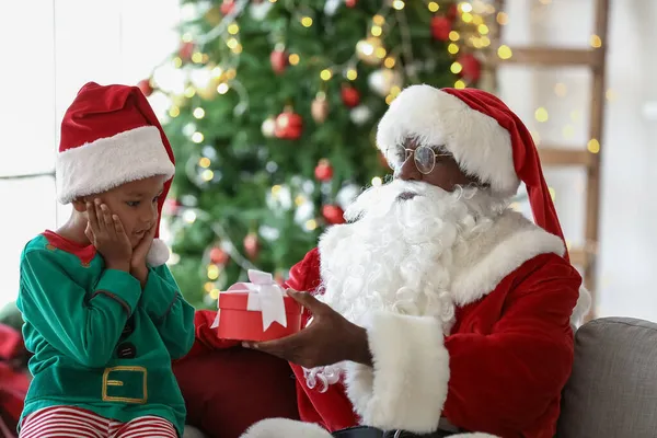Санта Клаус Дарит Подарок Маленькому Афроамериканскому Мальчику Дома — стоковое фото