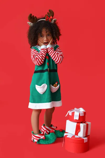 惊喜的小精灵带着红色背景的圣诞礼物 — 图库照片