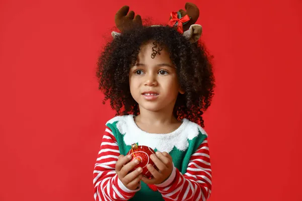 小さなアフリカ系アメリカ人の女の子とともにクリスマスボール上の赤い背景 — ストック写真