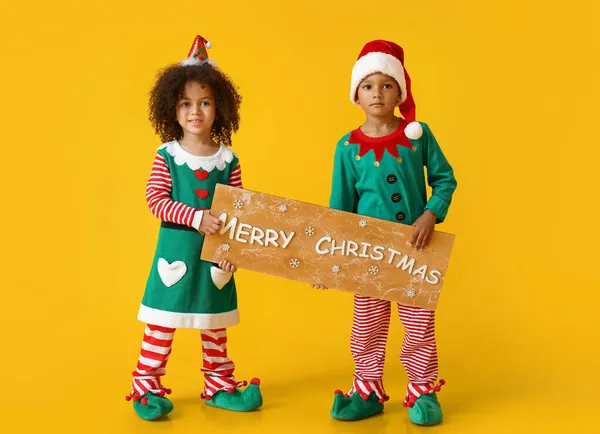Cute Little Elves Holding Board Text Merry Christmas Yellow Background — Stock Photo, Image