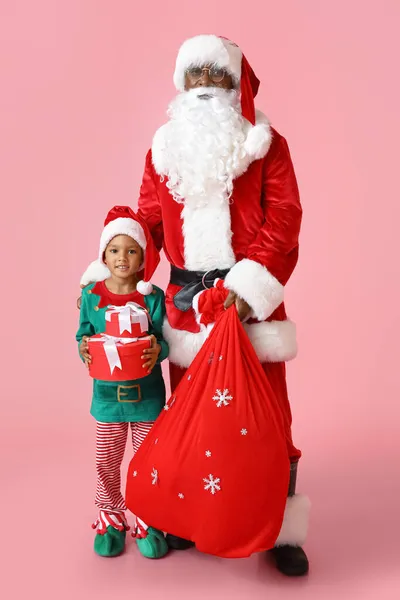 Niedliche Kleine Elfe Mit Weihnachtsmann Und Geschenken Auf Rosa Hintergrund — Stockfoto