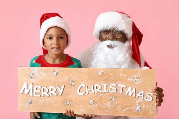 可爱的小精灵和圣诞老人拿着写着 快乐的圣诞节 的粉红背景的黑板 — 图库照片