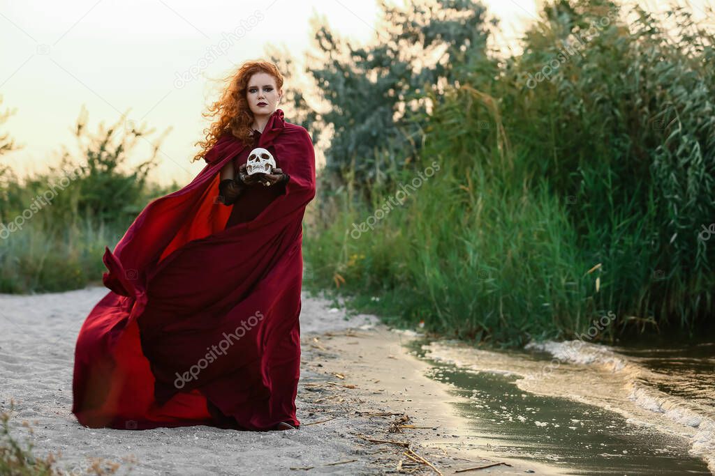 Young witch with skull outdoors