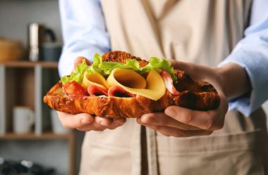 Mutfakta lezzetli kruvasan sandviçi olan kadın, yakın plan.