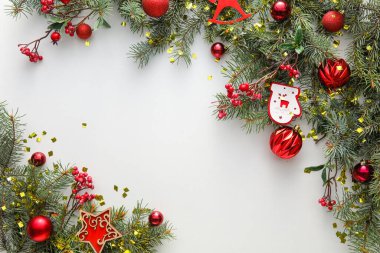 Beyaz arka planda köknar dalları ve Noel süslemeleri olan kompozisyon, yakın plan