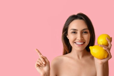 Taze limonları olan çıplak genç bir kadın, arka planda bir şey gösteriyor. Vegan Günü