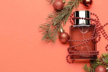 Bir şişe parfüm, köknar ağacı dalı ve arka planda Noel dekoru.