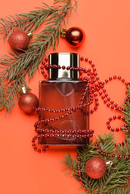 Parfüm şişesi, köknar ağacı dalı ve arka planda Noel dekoru