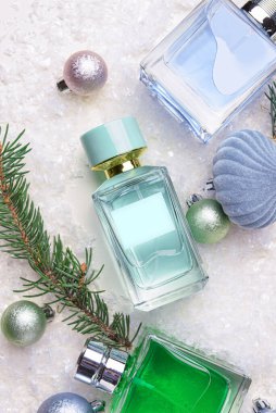 Parfüm şişeleri, köknar ağacı dalları ve arka planda Noel dekoru, yakın plan.