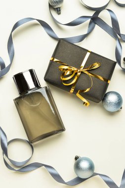 Parfüm şişesi, hediye kutusu ve arka planda Noel süsü.